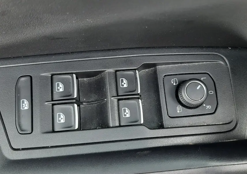 Gros plan sur les commandes de lève-vitres et réglage des rétroviseurs côté conducteur du Volkswagen T-Roc blanc toit noir.
