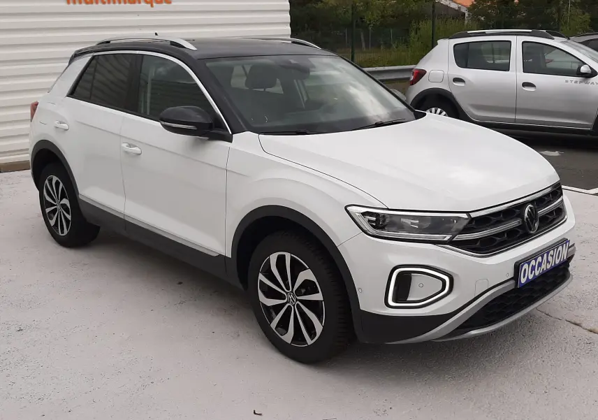 Volkswagen T-Roc blanc pur avec toit noir, vue 3/4 avant droit, jantes alliage et calandre distinctive.