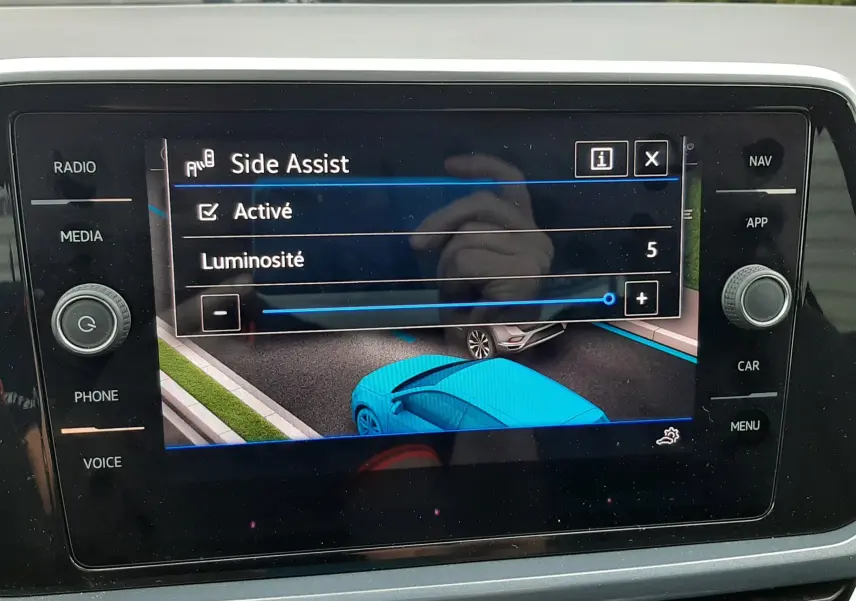 Vue intérieure sur l'écran tactile du Volkswagen T-Roc blanc, affichant l'activation de l'assistance de maintien de voie.