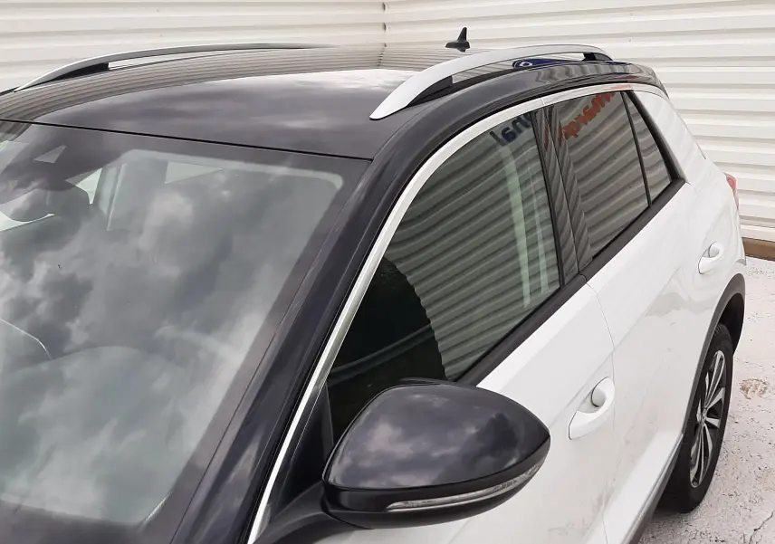Vue 3/4 avant droit du Volkswagen T-Roc blanc pur avec toit noir brillant et rétroviseur assorti.