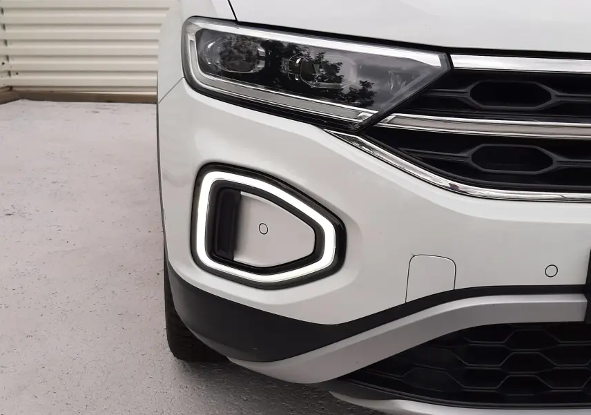 Gros plan sur l'avant gauche du Volkswagen T-Roc blanc pur avec éclairage LED et calandre noire.