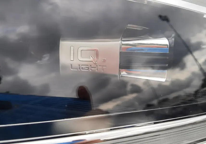 Gros plan sur le phare avant droit du Volkswagen T-Roc blanc pur avec inscription IQ.Light et détails chromés.