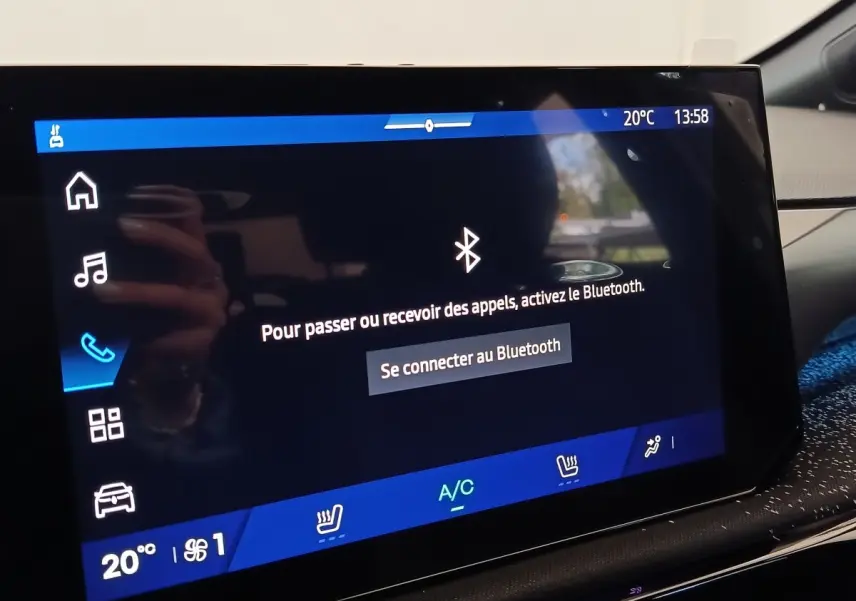 Écran tactile central de la Renault Clio gris foncé, affichage Bluetooth et commandes climatisation visibles.