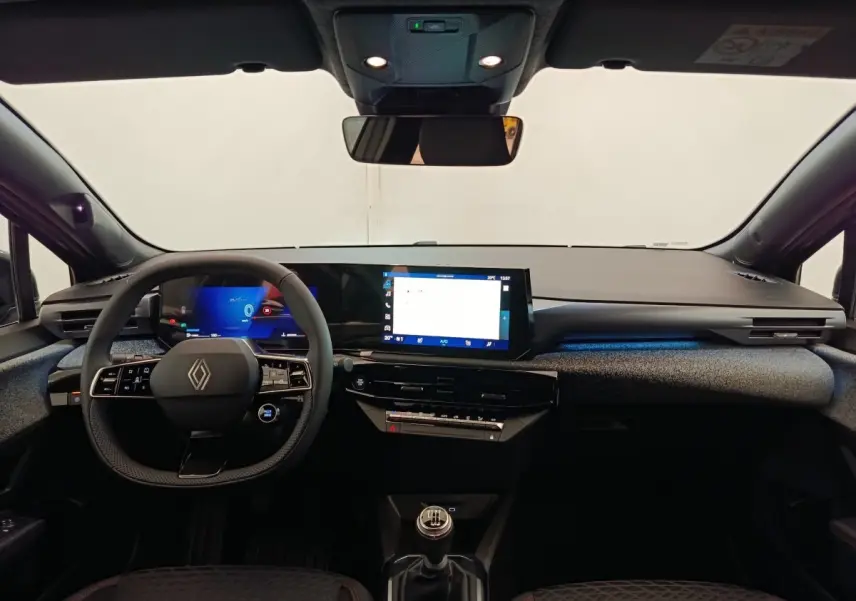 Vue intérieure avant de la Renault Clio techno TCe 115 gris foncé, tableau de bord moderne avec écran tactile et volant multifonctions.