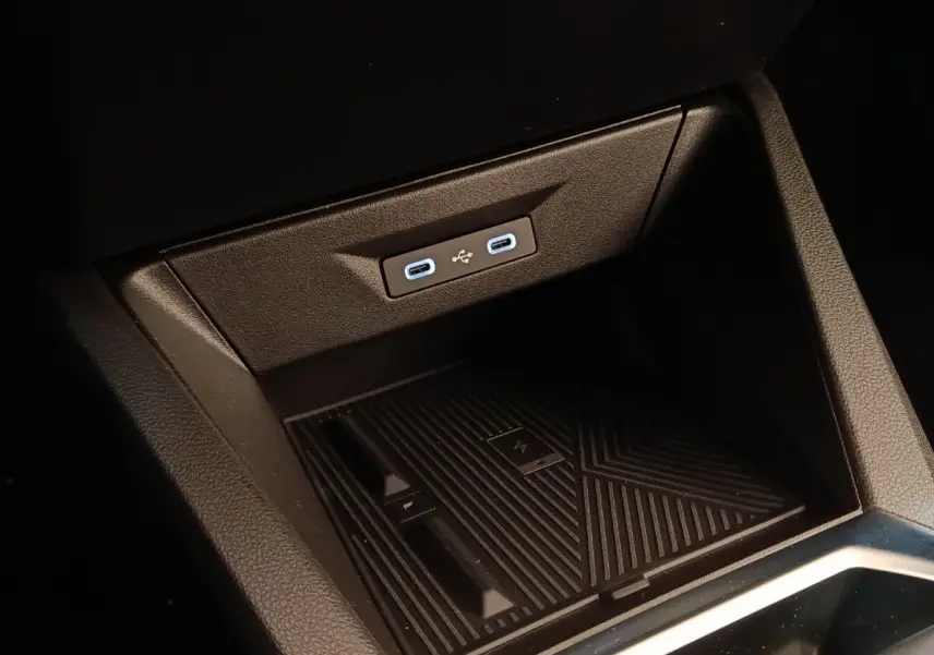Gros plan sur la console centrale de la Renault Clio Techno gris foncé, montrant les ports USB-C et le chargeur sans fil.