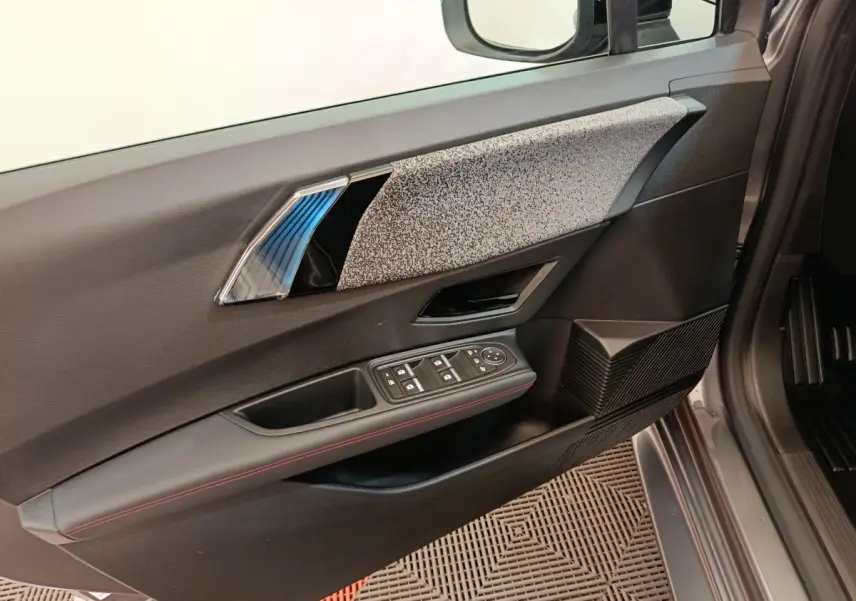 Vue intérieure côté gauche de la porte avant d’une Renault Clio gris foncé, avec commandes électriques et finition tissu gris.