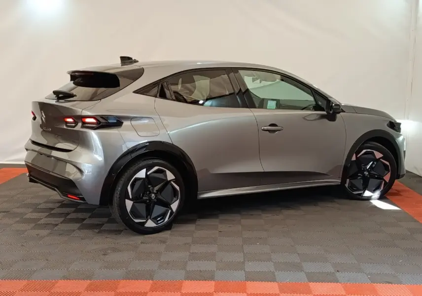 Vue de profil côté droit d'une Renault Clio Techno gris foncé avec jantes noires et feux arrière allumés.