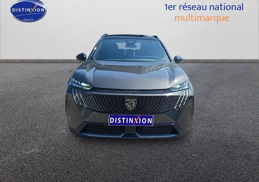 Vue frontale d'un Peugeot 5008 Hybrid 145 GT gris titane avec calandre noire et phares LED allumés