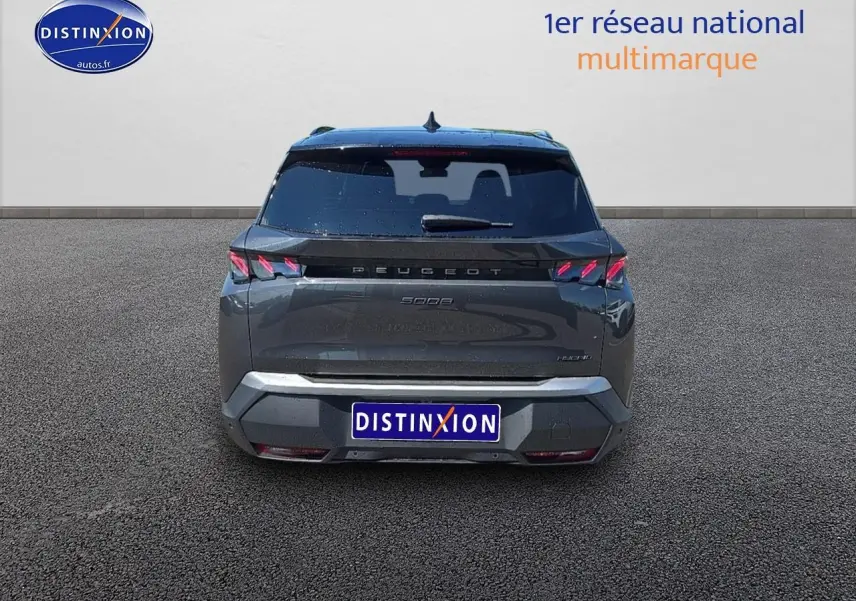 Vue arrière d'un Peugeot 5008 Hybrid 145 GT gris titane avec feux arrière LED et hayon électrique fermé.
