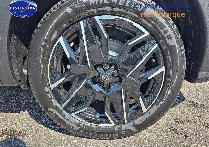 Gros plan sur la jante alu noire et argentée avec pneu Michelin du Peugeot 5008 Hybrid 145 gris titane.