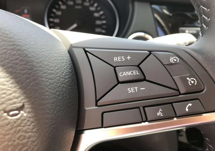 Gros plan sur les commandes du régulateur de vitesse au volant noir du Nissan Qashqai 1.3 DIG-T 2019.