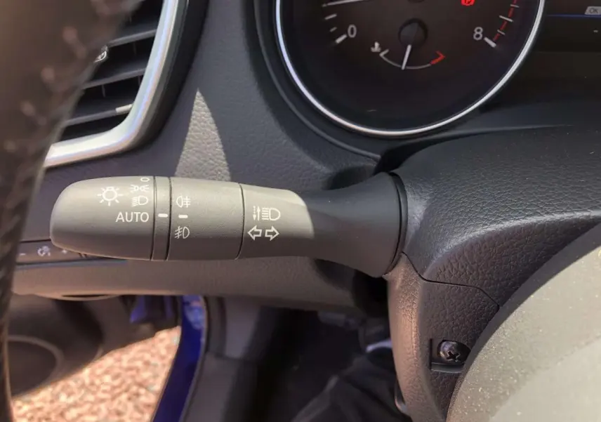 Gros plan sur la commande des feux et clignotants à gauche du volant du Nissan Qashqai bleu 2019.