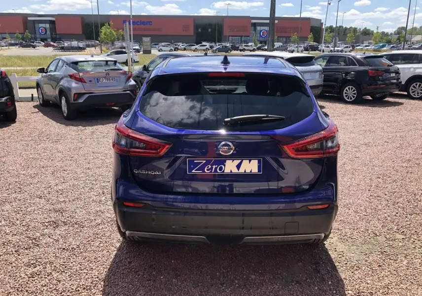 Vue arrière d'un Nissan Qashqai bleu métallisé, avec feux arrière allongés et plaque d'immatriculation "Zero KM" visible.
