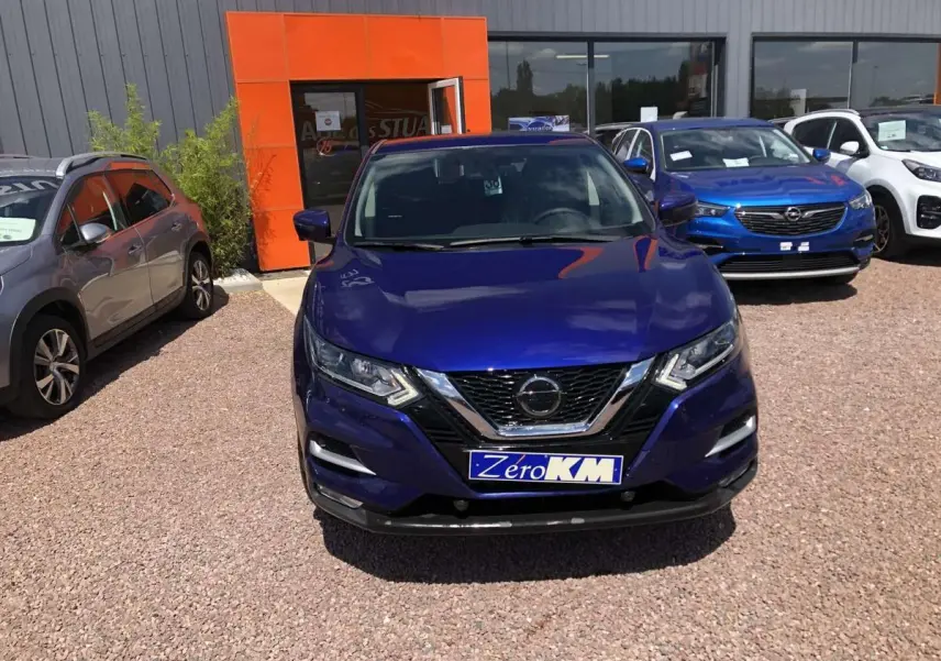 Vue de face d'un Nissan Qashqai bleu métallisé avec calandre chromée et plaque d'immatriculation Zero KM.