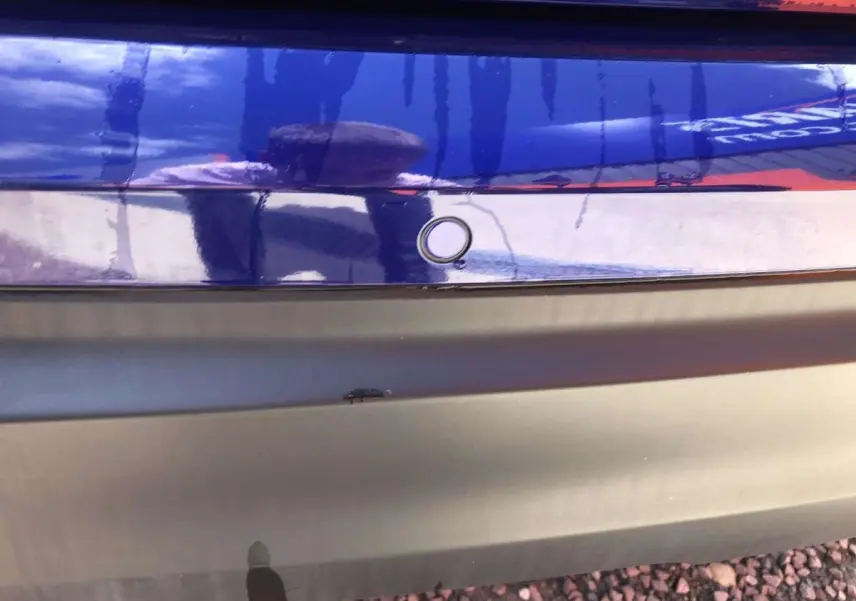 Gros plan sur le pare-chocs arrière bleu métallisé du Nissan Qashqai 2019 avec capteur de stationnement visible.