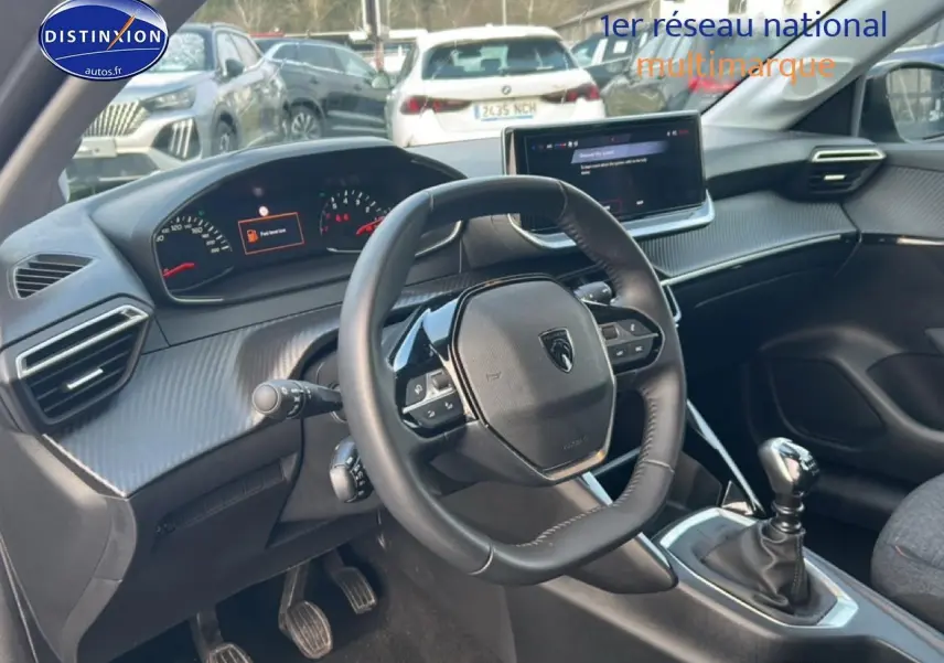 Vue intérieure côté conducteur du Peugeot 208 gris Artense, volant compact et écran tactile central visible.