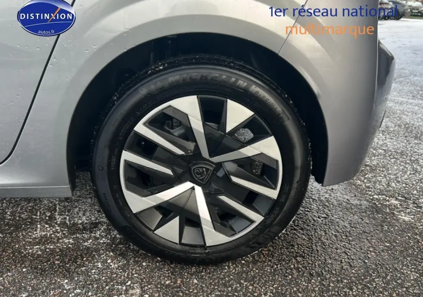 Gros plan sur la roue avant droite gris artense d'une Peugeot 208 1.2 100 style avec jante au design géométrique.