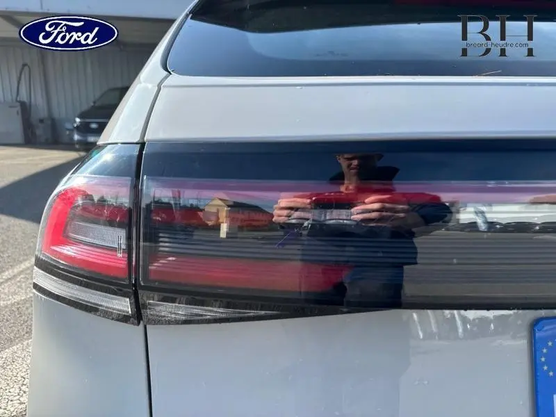 Feu arrière gauche en gros plan d'une Volkswagen Taigo blanc pur, avec reflet et logo Ford en arrière-plan.