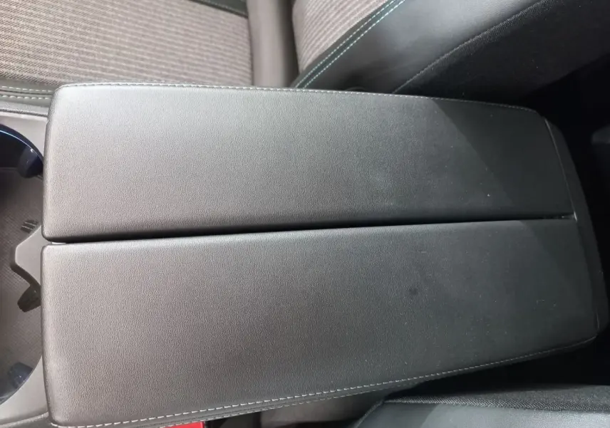 Vue rapprochée de l'accoudoir central noir en cuir avec surpiqûres blanches dans l'habitacle du Peugeot 5008 gris foncé.