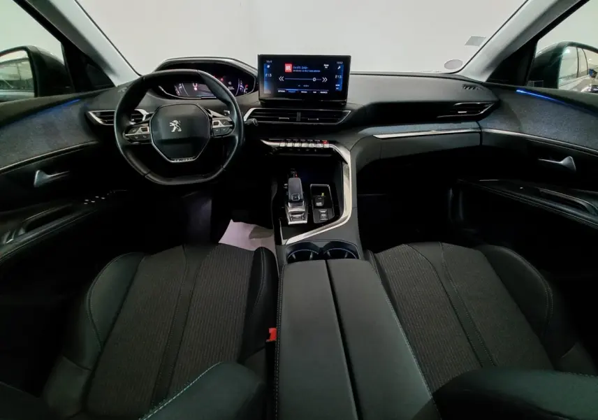 Vue intérieure avant du Peugeot 5008 2021 avec tableau de bord noir, volant compact et écran tactile central lumineux.