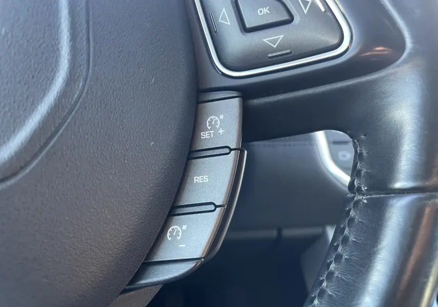 Gros plan sur la partie gauche du volant en cuir noir du Range Rover Evoque 2016, avec commandes de régulateur de vitesse.