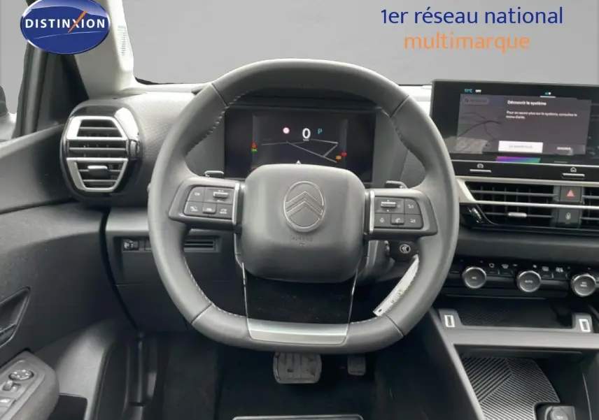 Vue frontale de l'intérieur du Citroën C4 blanc métal, avec volant multifonction et tableau de bord numérique.