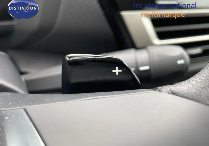 Gros plan sur la palette de changement de vitesse + côté droit du volant d’une Citroën C4 blanche métal.