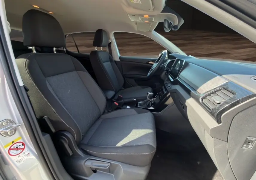 Vue intérieure côté droit du Volkswagen T-Cross gris clair 2025, montrant les sièges avant et le tableau de bord.