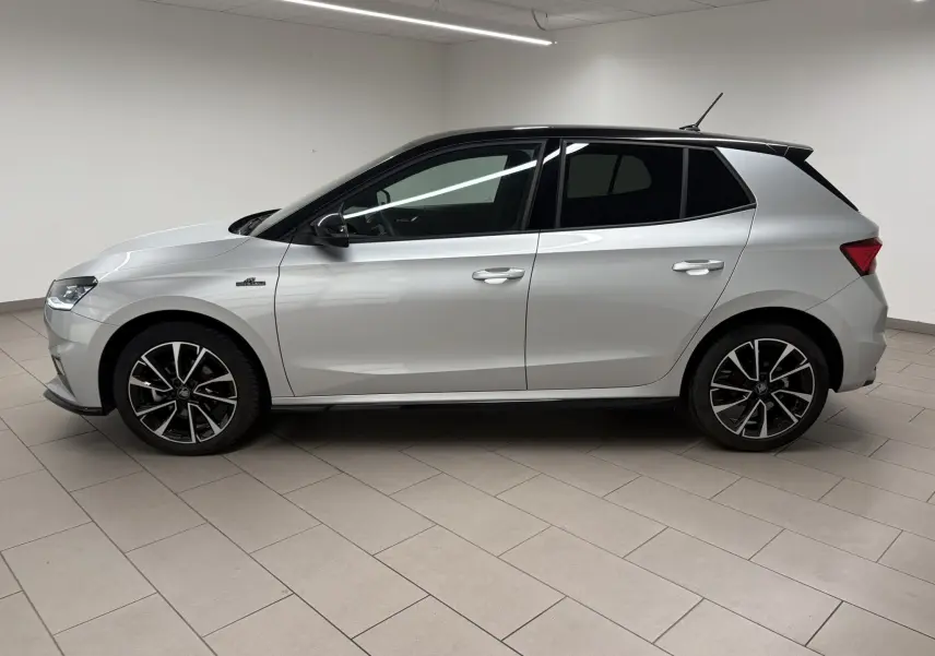 Vue de profil côté gauche d'une Skoda Fabia 2025 gris argent avec toit noir et jantes noires à motifs argentés.