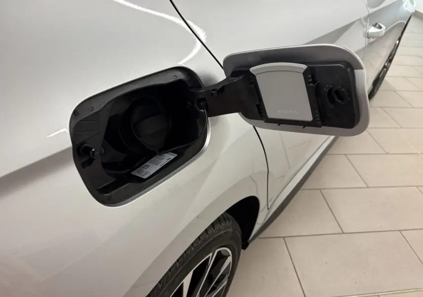 Gros plan sur la trappe à carburant ouverte côté gauche d'une Skoda Fabia gris argent avec toit noir, vue partielle de la roue arrière.
