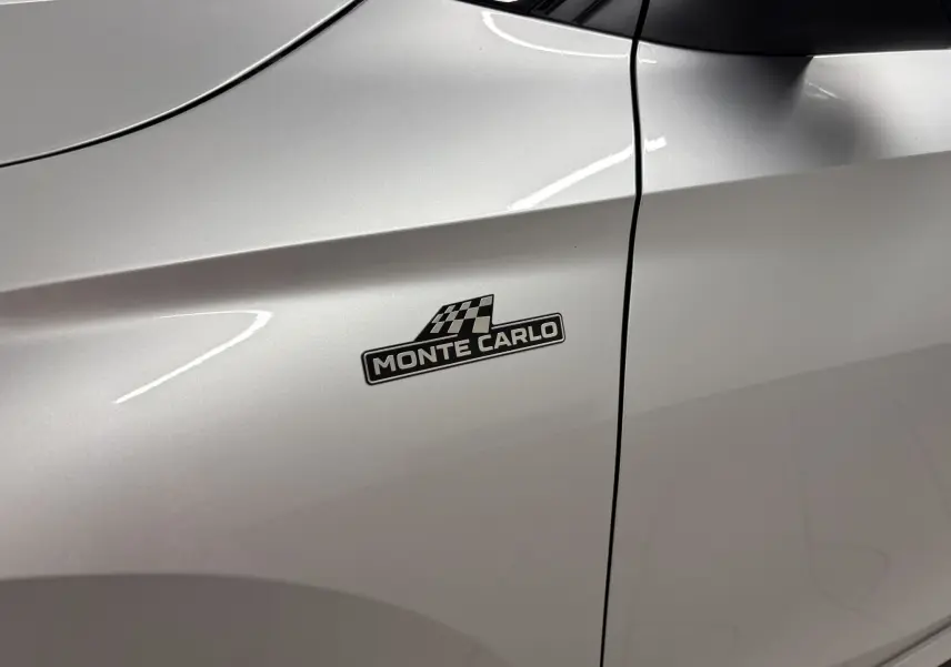 Gros plan sur l'aile avant gauche gris argent d'une Skoda Fabia Monte Carlo avec logo distinctif noir et damier.