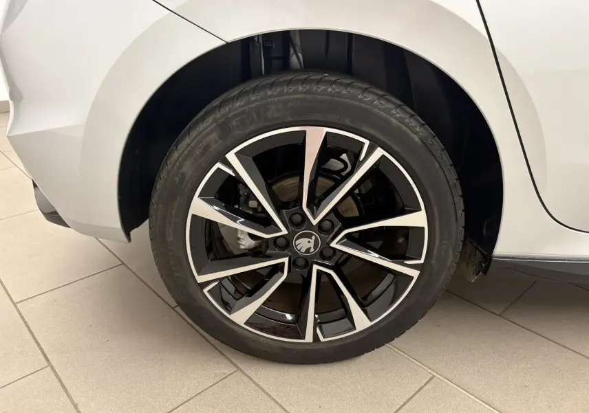 Gros plan sur la roue arrière droite d'une Skoda Fabia 2025 gris argent avec jante noire et argentée au design moderne.