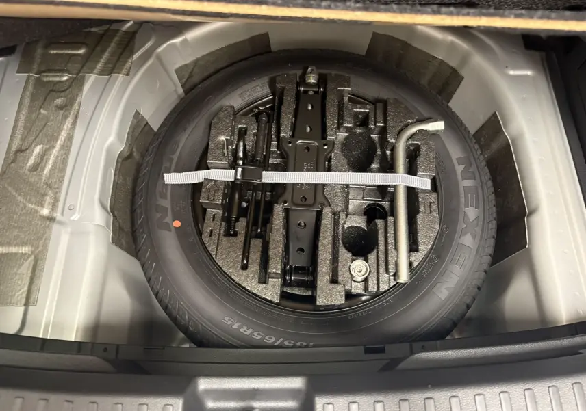 Vue plongeante sur la roue de secours et les outils rangés dans le double plancher du coffre de la Skoda Fabia 2025.