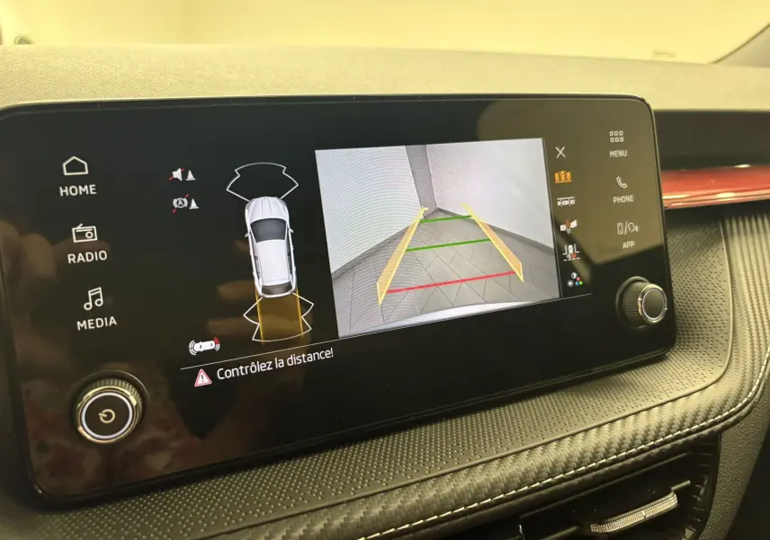 Écran central de la Skoda Fabia 2025 montrant la caméra de recul avec guidage dynamique et alertes de distance.