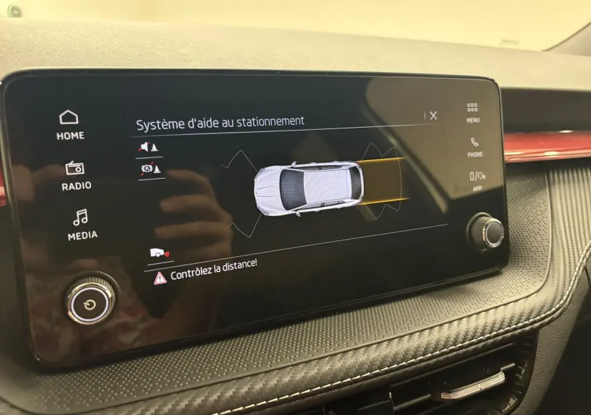 Écran central du système d'aide au stationnement de la Skoda Fabia 2025, affichant une vue aérienne du véhicule gris argent avec toit noir.