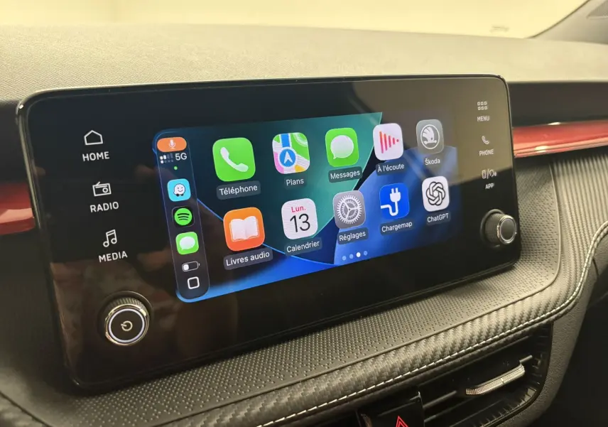 Écran tactile central de la Skoda Fabia 2025 avec interface connectée et tableau de bord gris avec insert rouge.