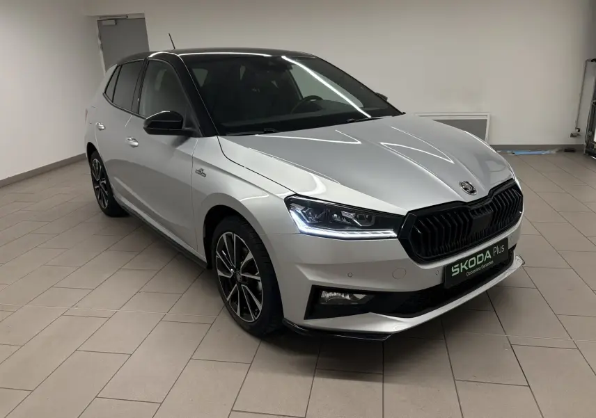 Vue 3/4 avant droite d'une Skoda Fabia 2025 gris argent avec toit noir et calandre noire sportive.
