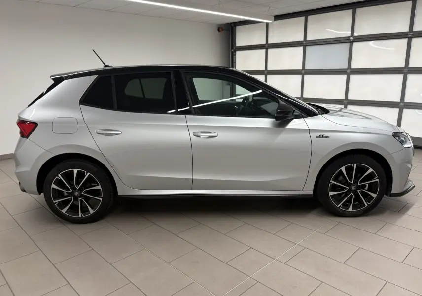 Vue de profil côté gauche d'une Skoda Fabia 2025 gris argent avec toit noir et jantes noires à motifs argentés.