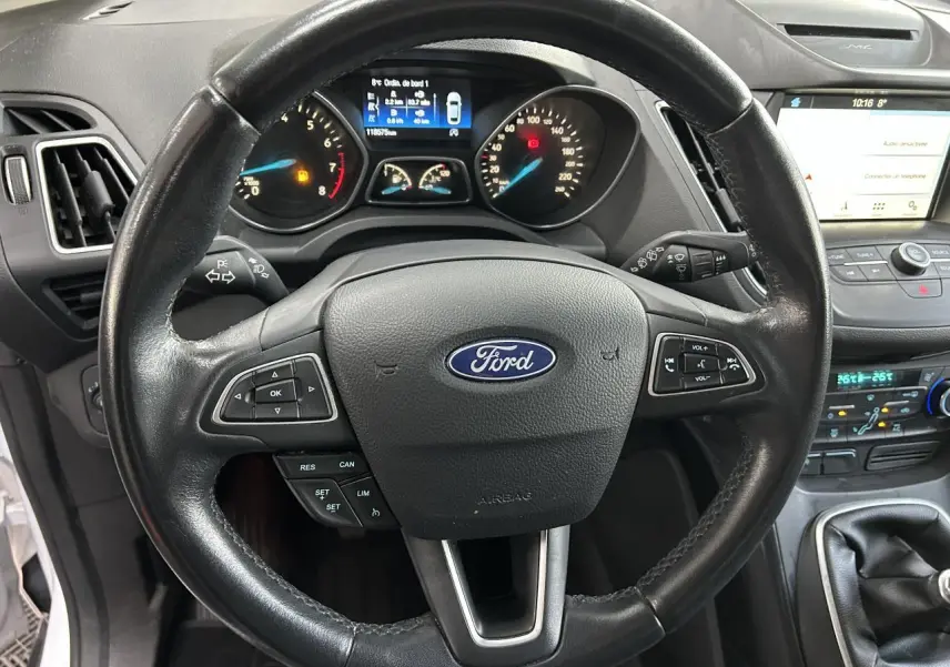 Vue rapprochée du volant noir Ford C-MAX 2018 avec tableau de bord et écran tactile SYNC 3 en arrière-plan.