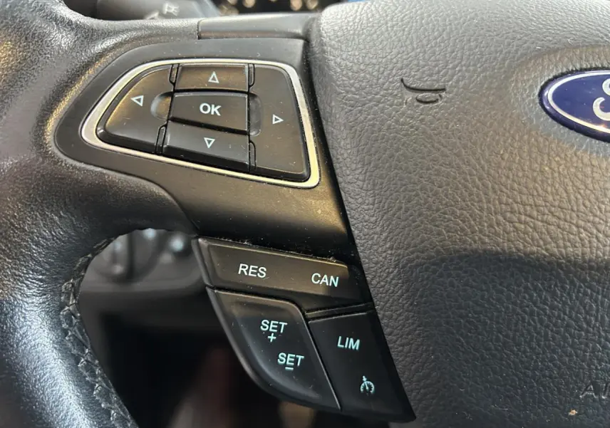 Gros plan sur le volant noir de la Ford C-MAX 2018, avec commandes de régulateur de vitesse et logo Ford visible.