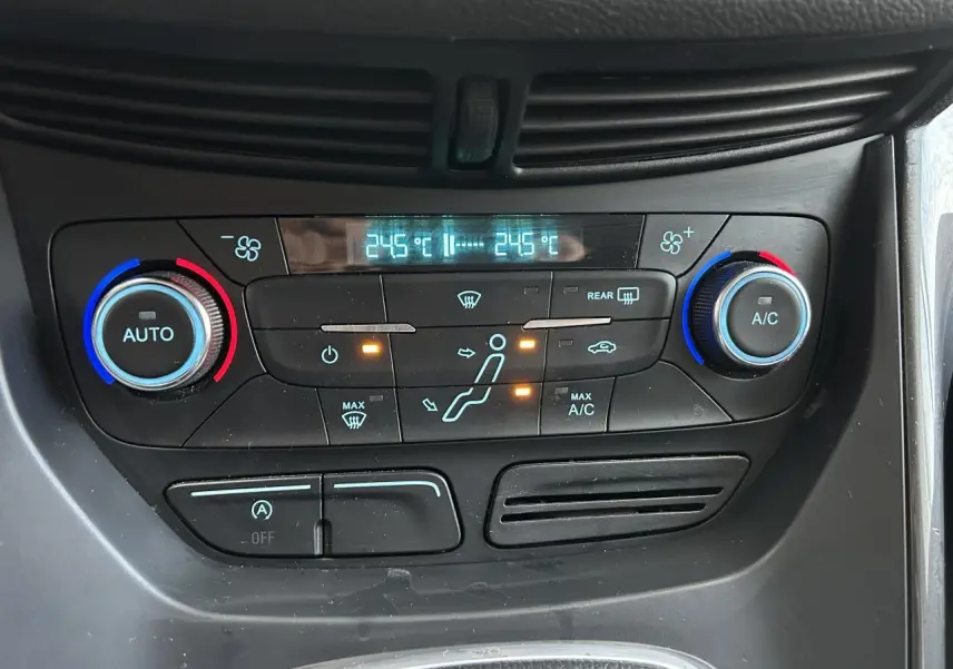 Panneau de climatisation bi-zone avec réglages à boutons rotatifs bleus et rouges dans une Ford C-MAX blanche vue de face.