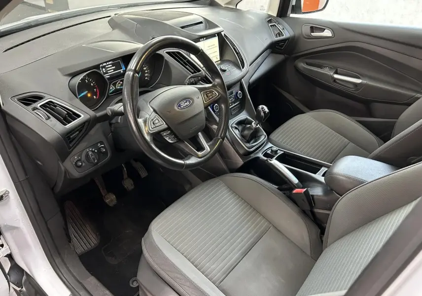 Intérieur avant du Ford C-MAX blanc 2018, vue côté conducteur montrant tableau de bord, volant et sièges gris.