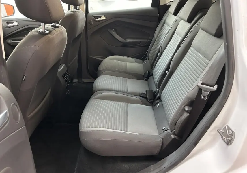 Vue latérale côté droit de l'habitacle arrière d'un Ford C-MAX blanc, sièges tissu gris et ceintures visibles.
