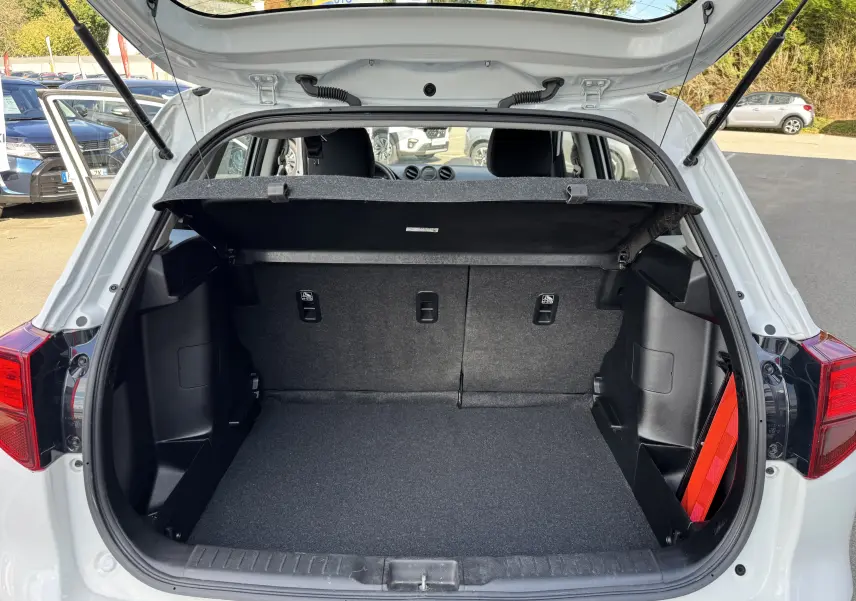 Coffre ouvert d'un Suzuki Vitara blanc 2023, vue arrière montrant l'espace de chargement et la tablette cache-bagages.