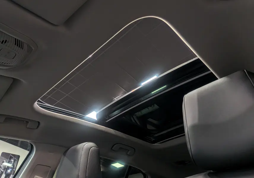 Toit ouvrant panoramique ouvert vu de l'intérieur avant d'un Citroën C5 Aircross hybride blanc avec sièges noirs.