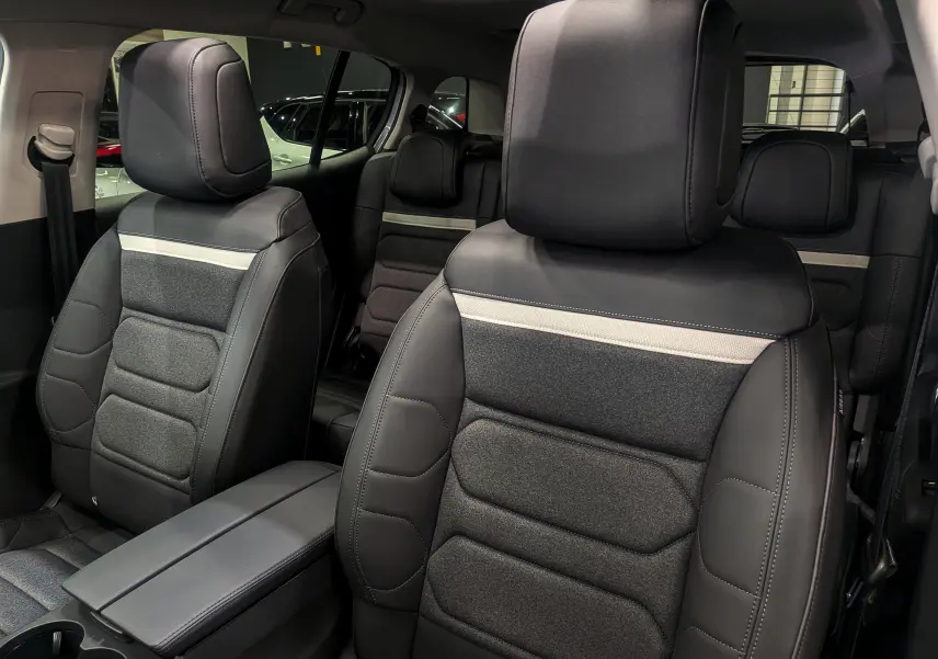 Gros plan sur les sièges avant en cuir noir et tissu gris du Citroën C5 Aircross hybride 2025, intérieur spacieux et moderne.