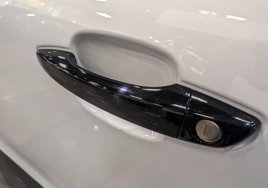 Poignée de porte noire en gros plan sur la portière blanche d'un Citroën C5 Aircross hybride 2025.