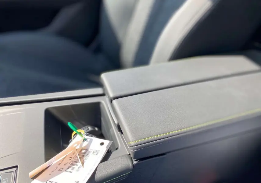 Gros plan sur l'accoudoir central gris de la Peugeot 308 GT 2025 avec clé et étiquette posées dessus.