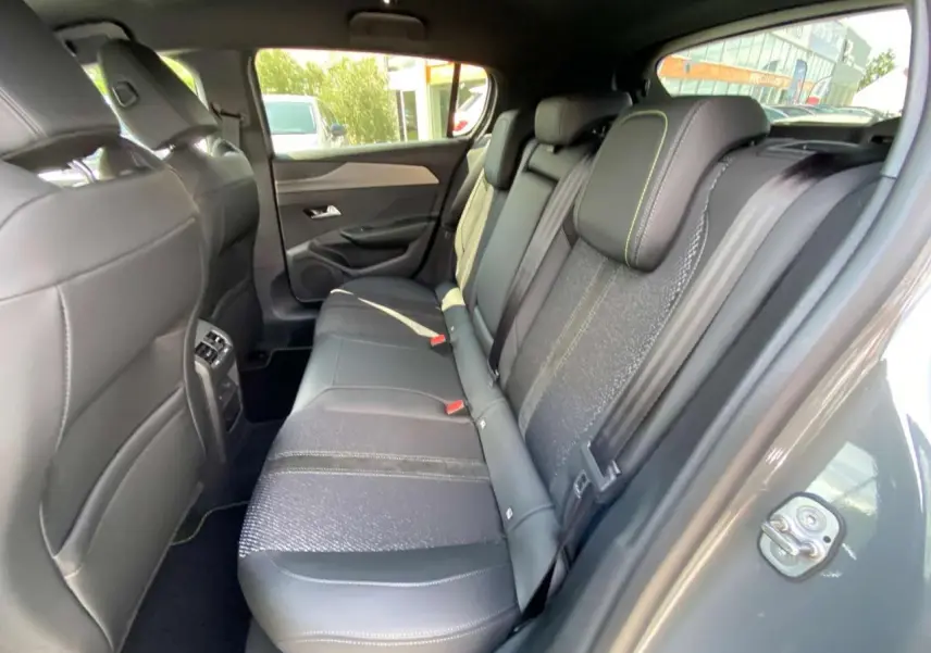 Vue intérieure côté droit des sièges arrière en cuir noir avec surpiqûres vertes d'une Peugeot 308 GT 2025 gris selenium.