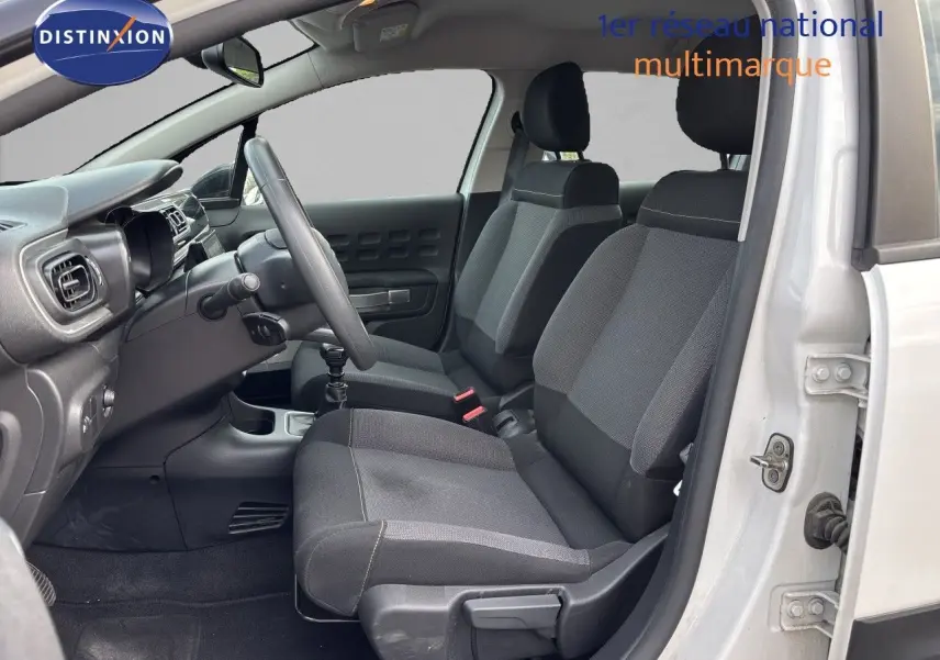 Vue intérieure côté conducteur de la Citroën C3 blanche banquise 2022, sièges tissu gris et tableau de bord noir.